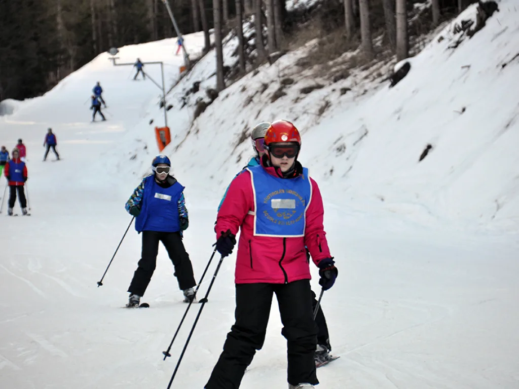 Zwei Skifahrende stehen nebeneinander auf der Piste.